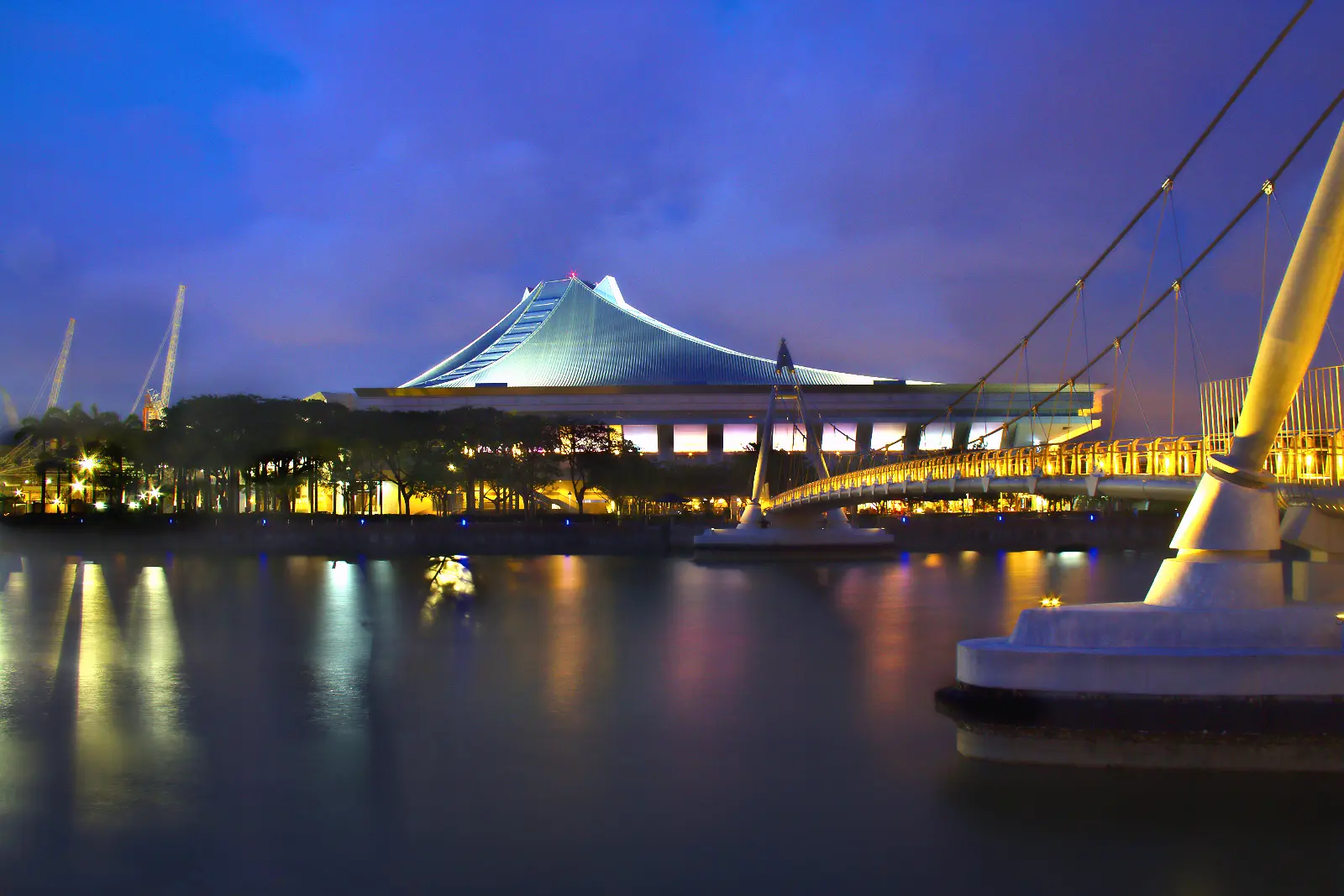 Singapore Indoor Stadium roof lit at dusk beside the Kallang waterway