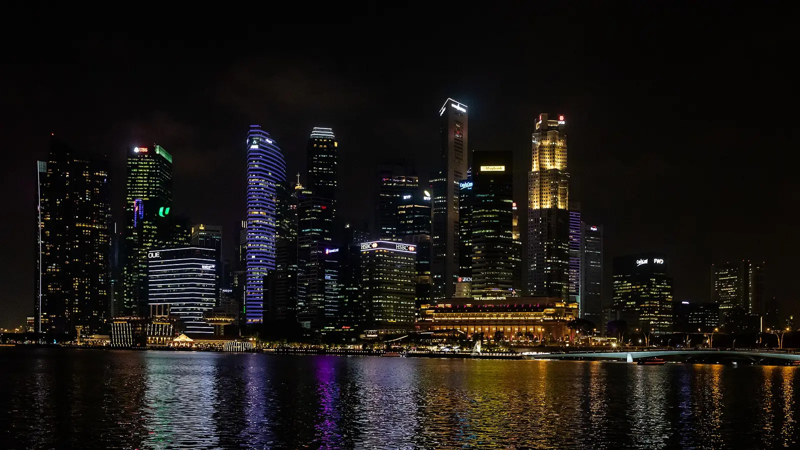 Downtown Singapore towers lit at night across Marina Bay